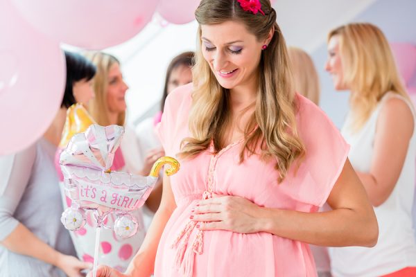 Pregnant girl celebrating baby shower party with friends, showing her baby belly